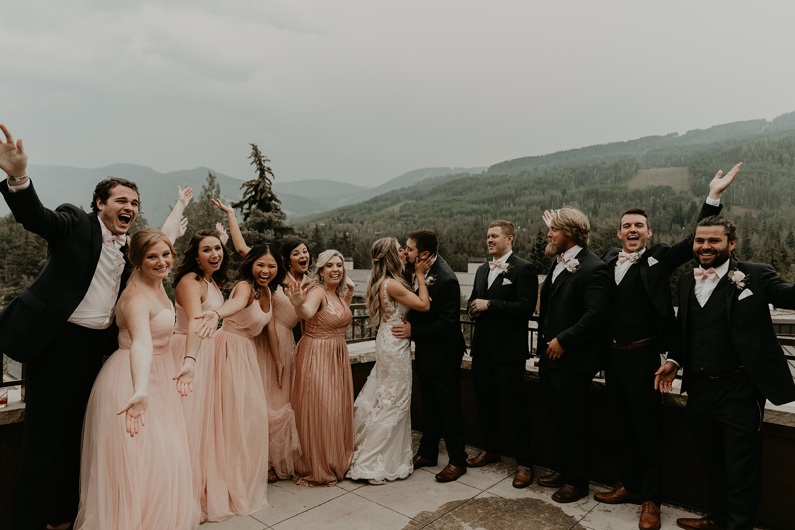 bride and groom share a kiss as their wedding party looks on 