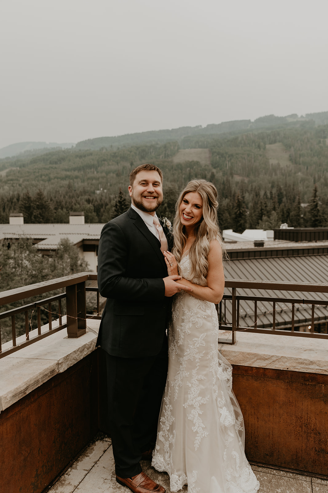 bride and groom pose with the mountains in the background