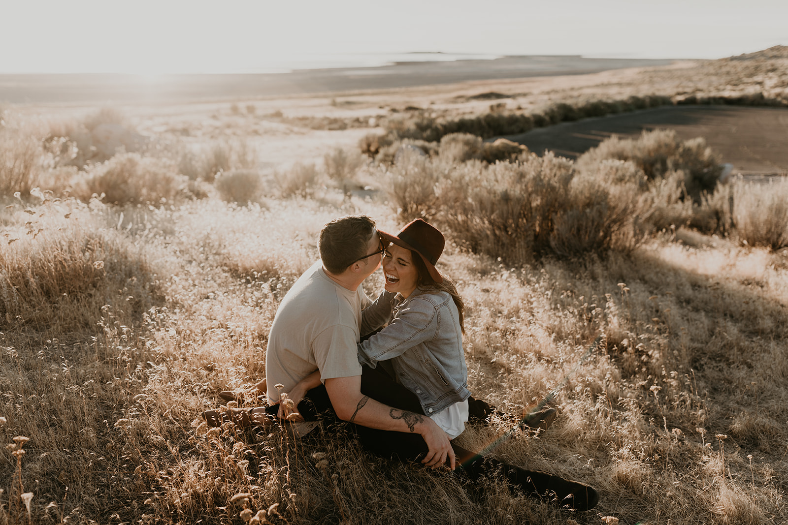 couple sit together in a prairie field during their Engagement photos in Utah