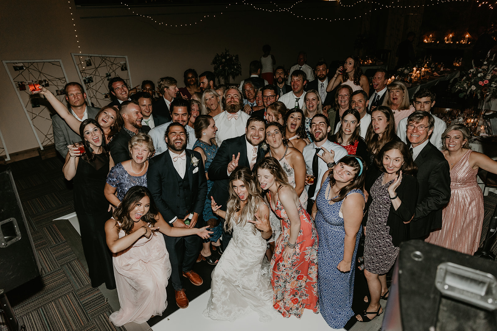 wedding guests pose with the bride and groom for a photo