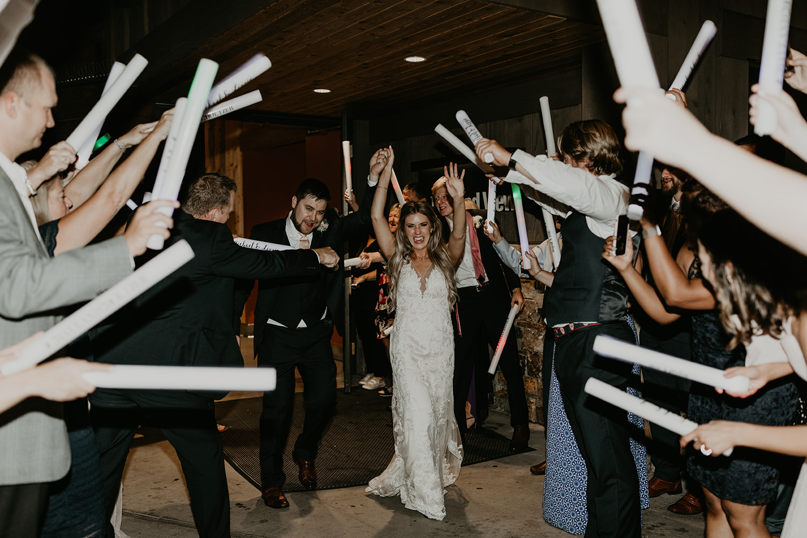 bride and groom exit their wedding through an arm tunnel and wedding favors 