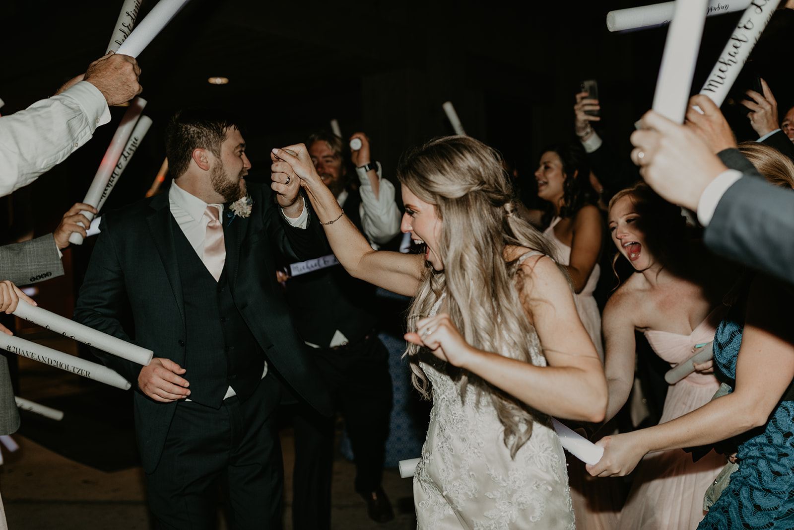 bride and groom exit their wedding through an arm tunnel and wedding favors 