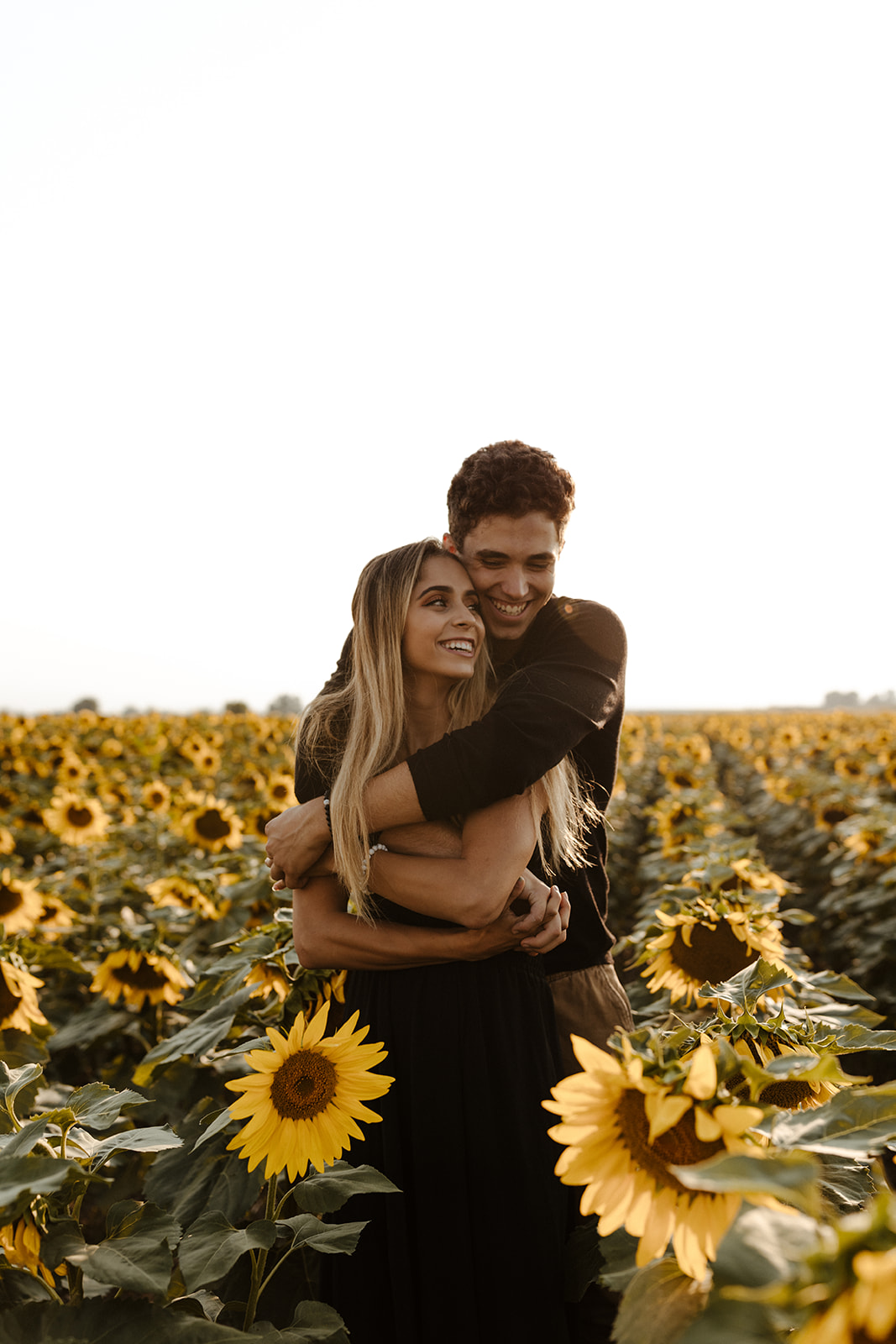 couple pose candidly during their dreamy Denver sunflower field engagement photoshoot