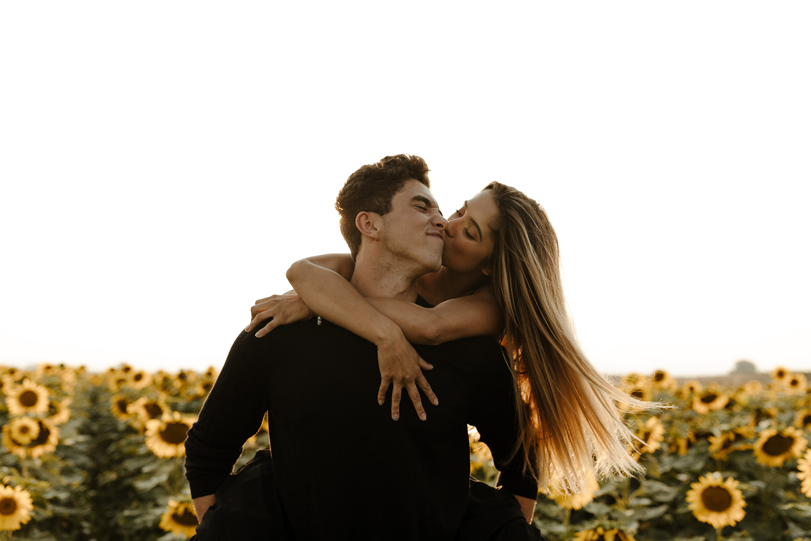 couple pose candidly during their dreamy Denver sunflower field engagement photoshoot