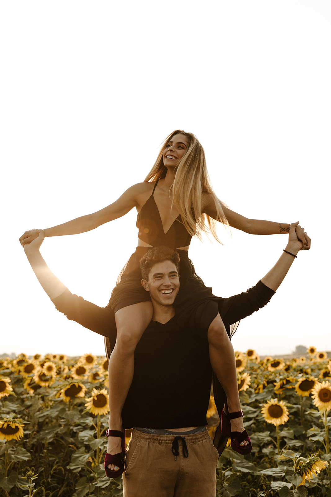 couple pose candidly during their dreamy Denver sunflower field engagement photoshoot