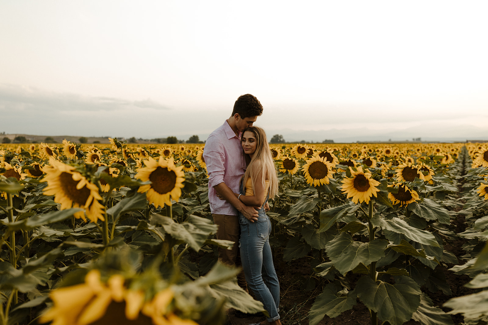 beautiful couple stand together during their Denver sunflower field engagement photos