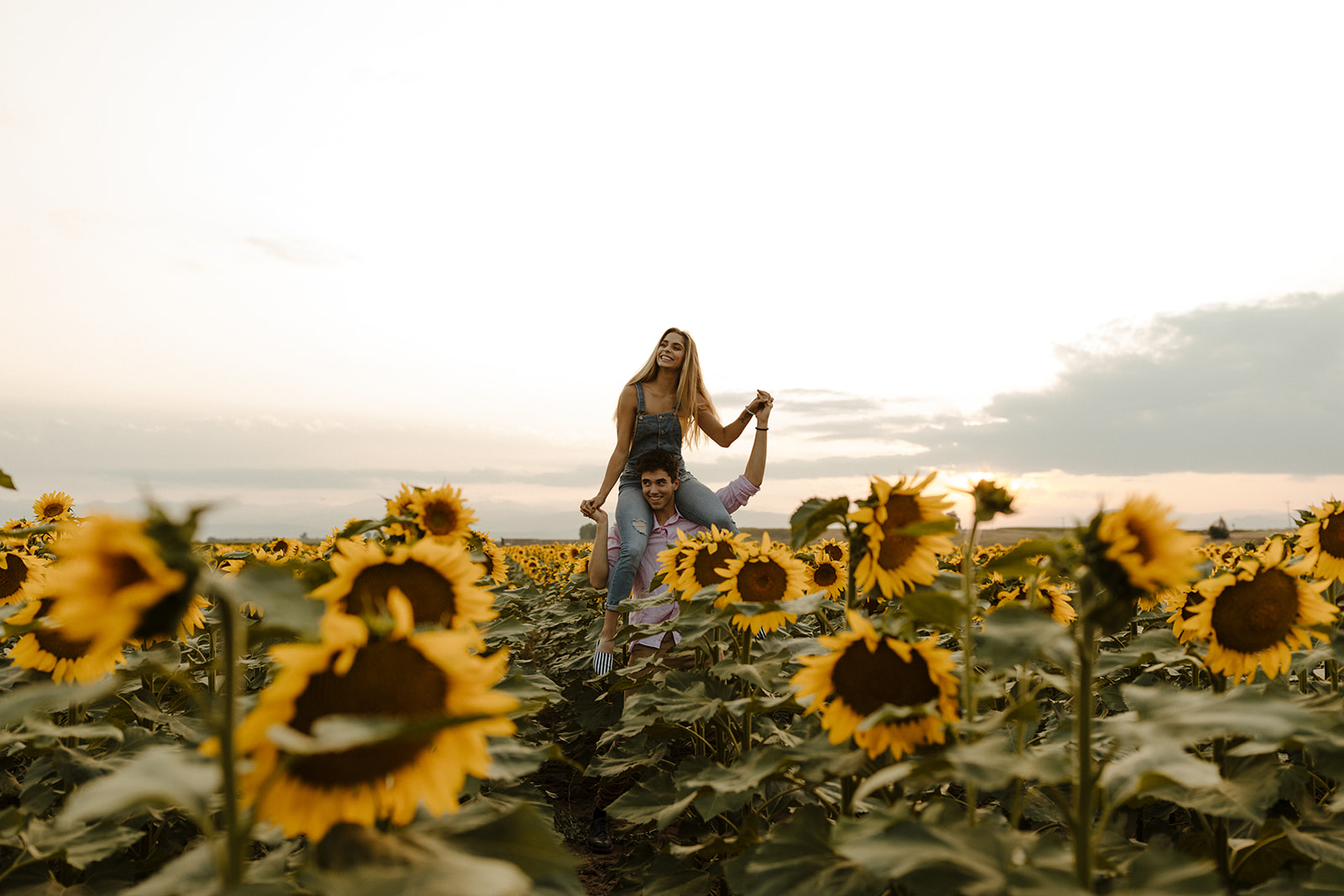 couple pose candidly during their dreamy Denver sunflower field engagement photoshoot