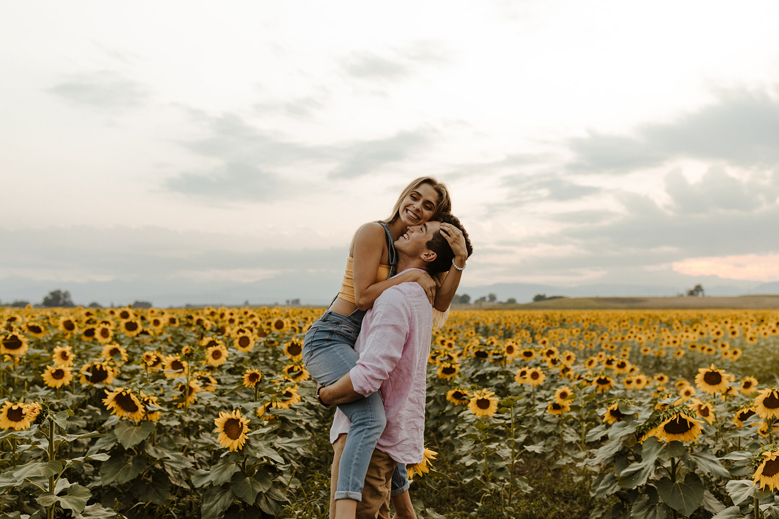 beautiful couple stand together during their Denver sunflower field engagement photos