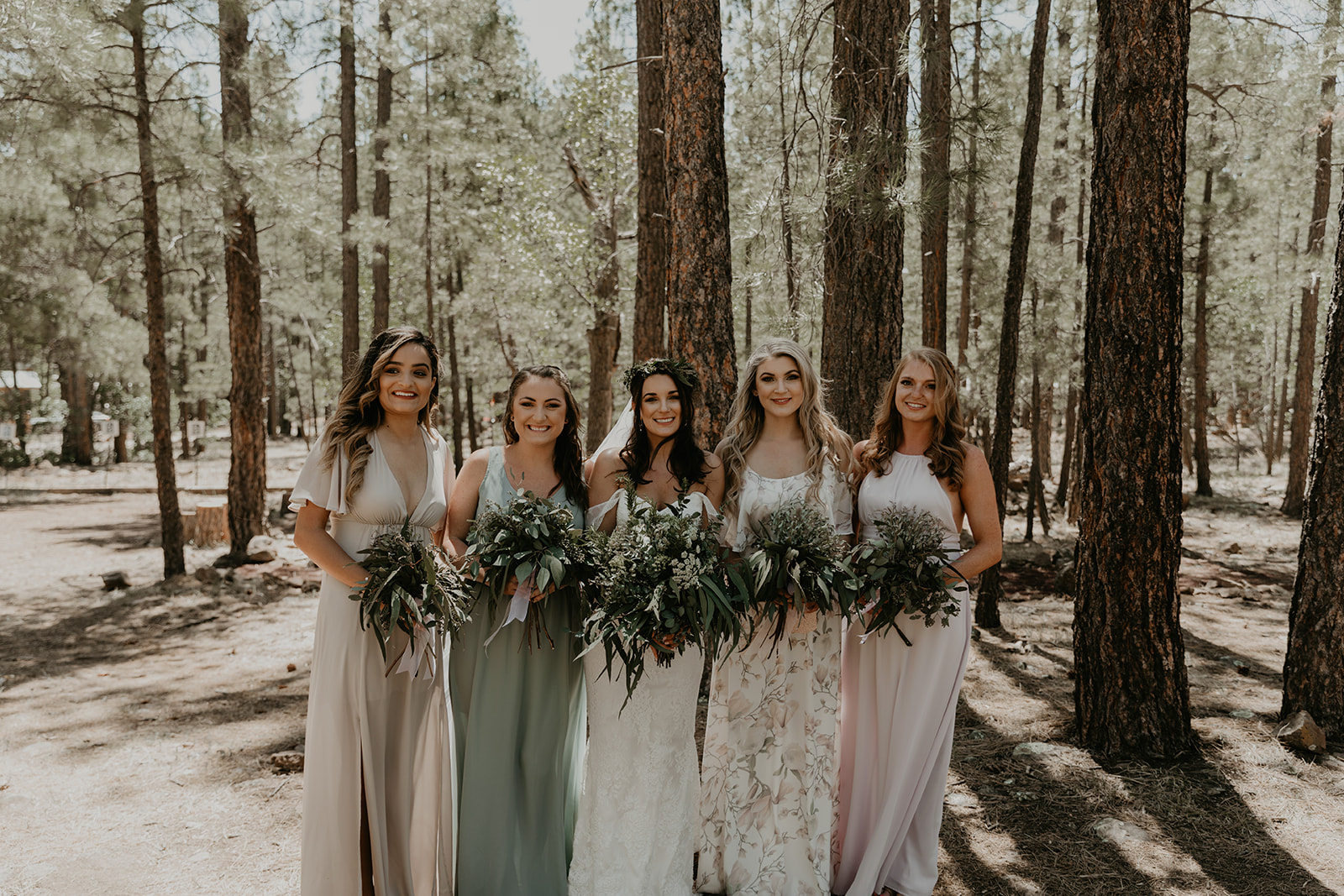 bridesmaids pose together with the bride in the Arizona forrest