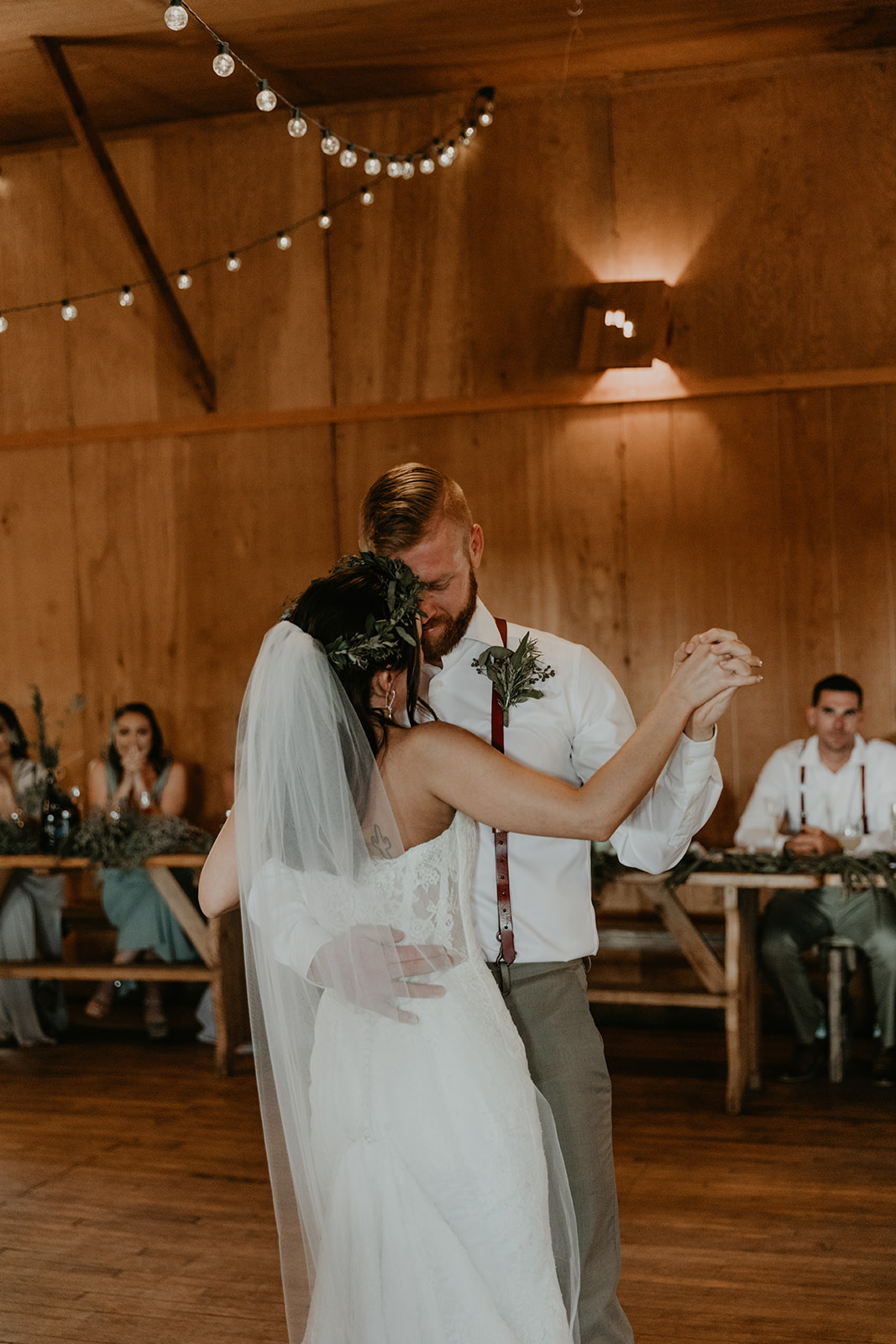 bride and groom share their first dance as their guests look on 