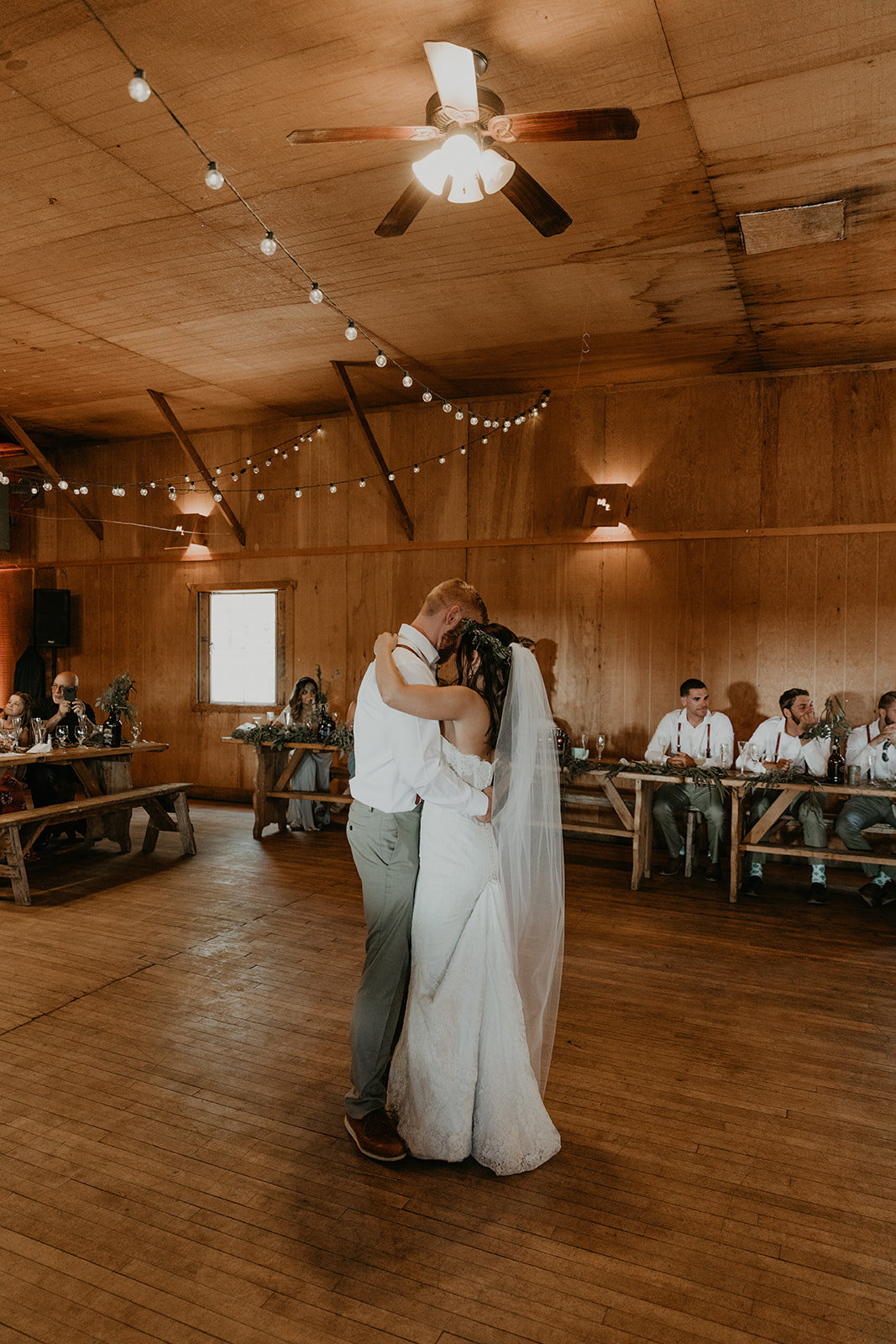 bride and groom share their first dance as their guests look on 