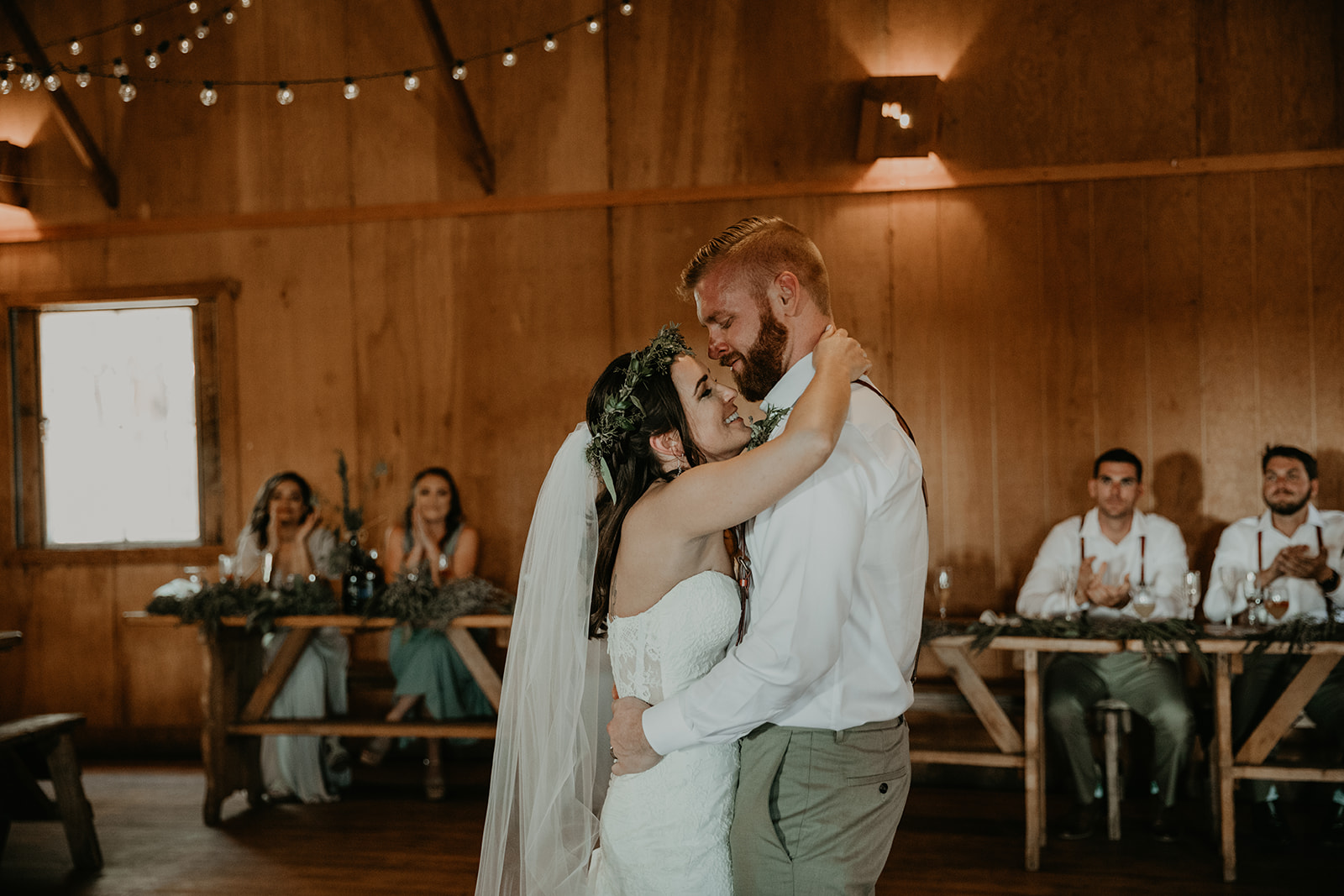 bride and groom share their first dance as their guests look on 