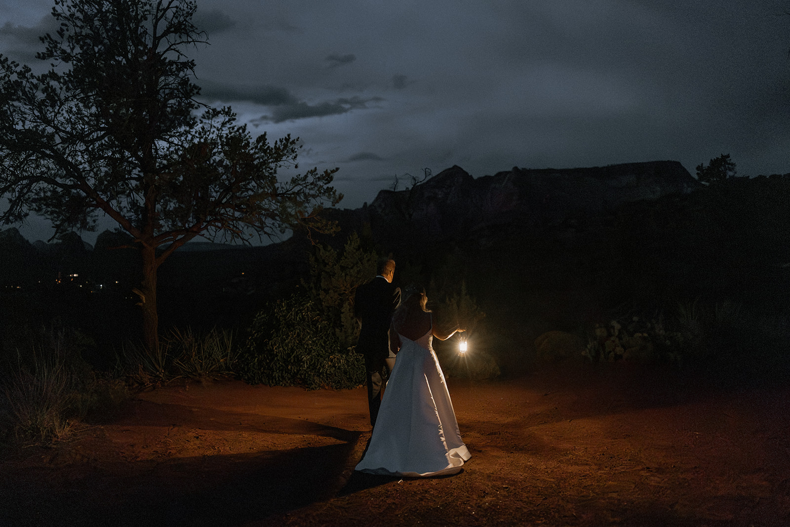 bride and groom pose with a lantern in the stunning Arizona nature