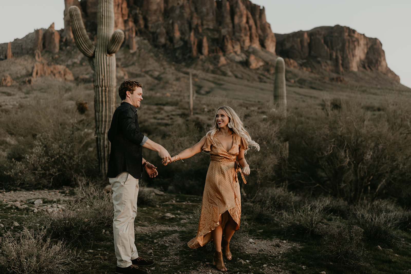 couple pose beside the cactus during their desert engagement photoshoot