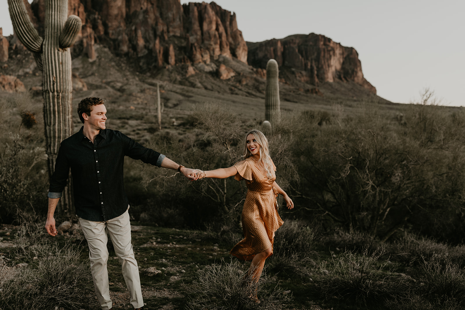 couple pose beside the cactus during their desert engagement photoshoot