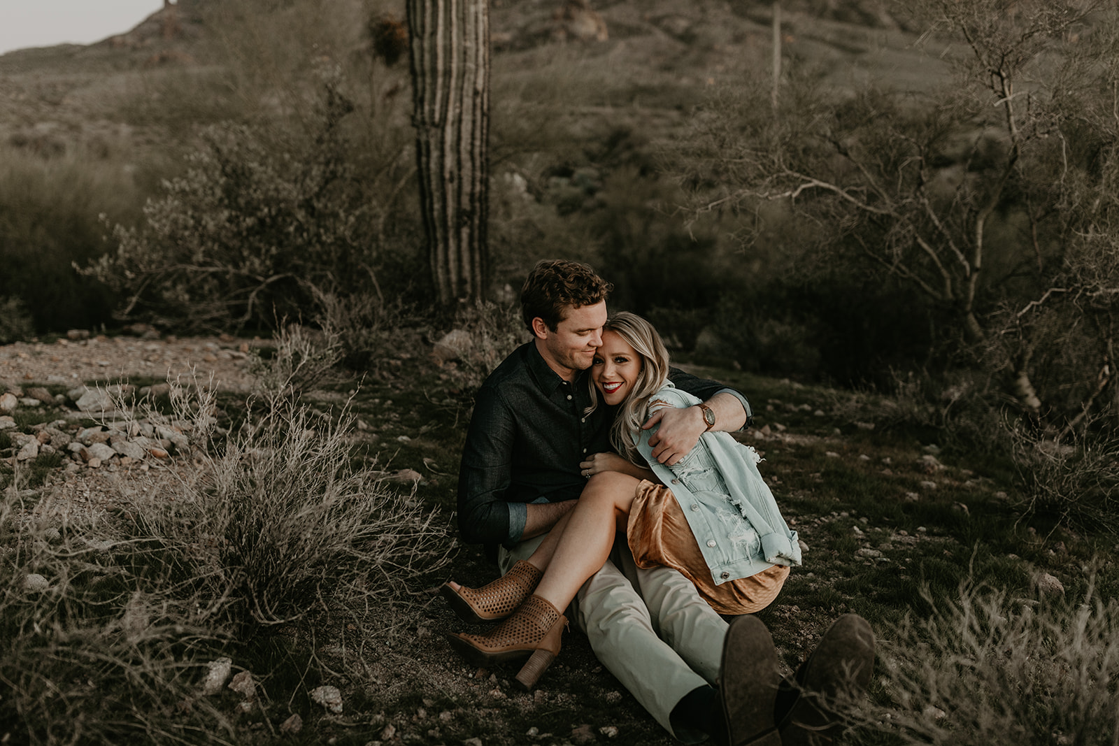 couple pose beside the cactus during their desert engagement photoshoot