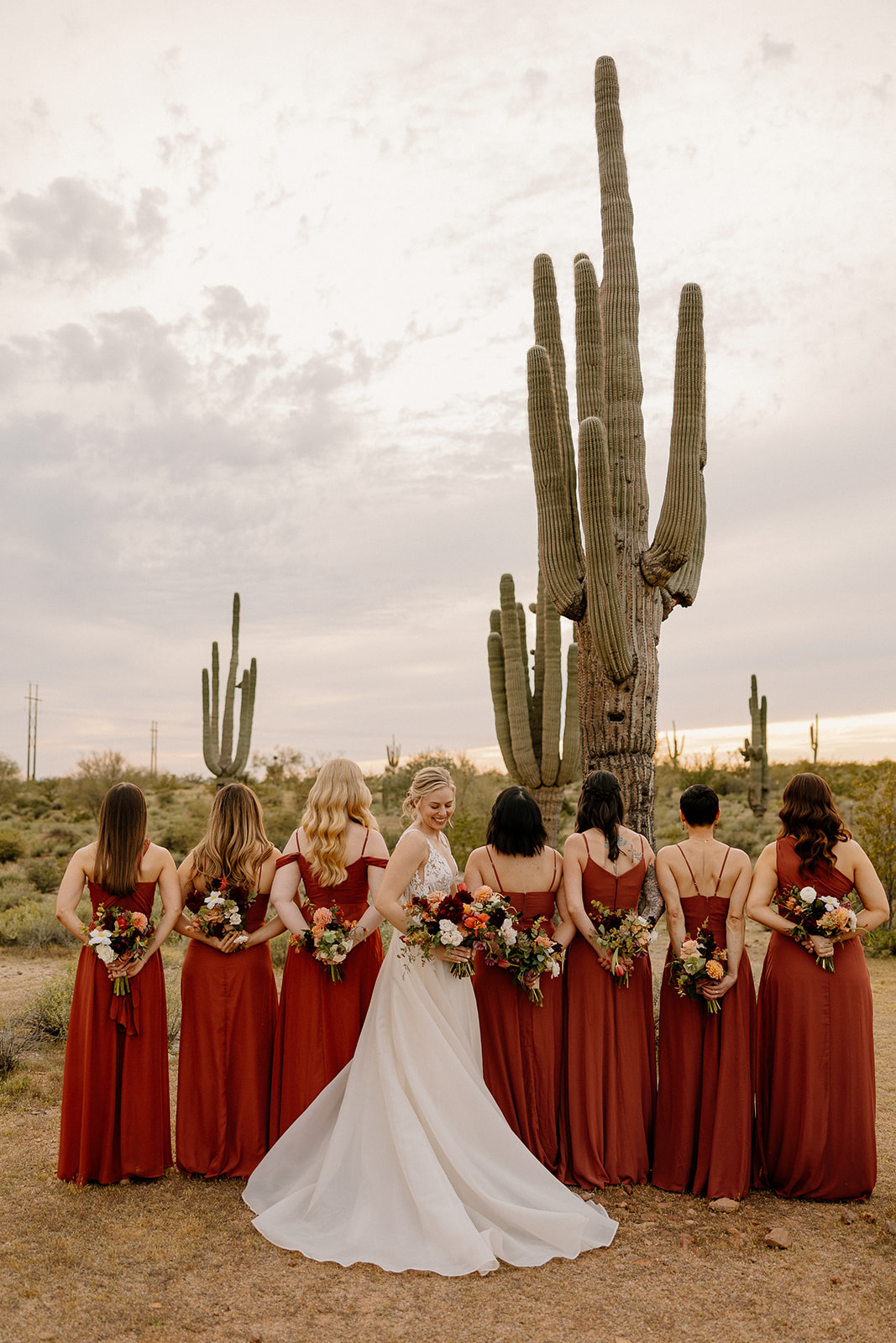 bride poses with her bridemaids after her wedding day