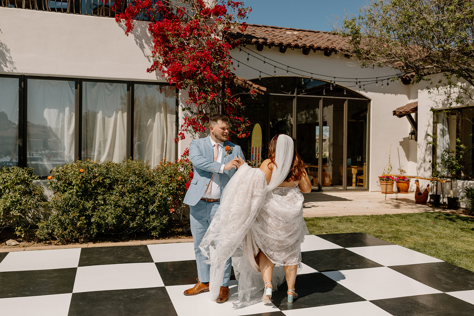 bride and groom share a dance on the checkerboard dance floor