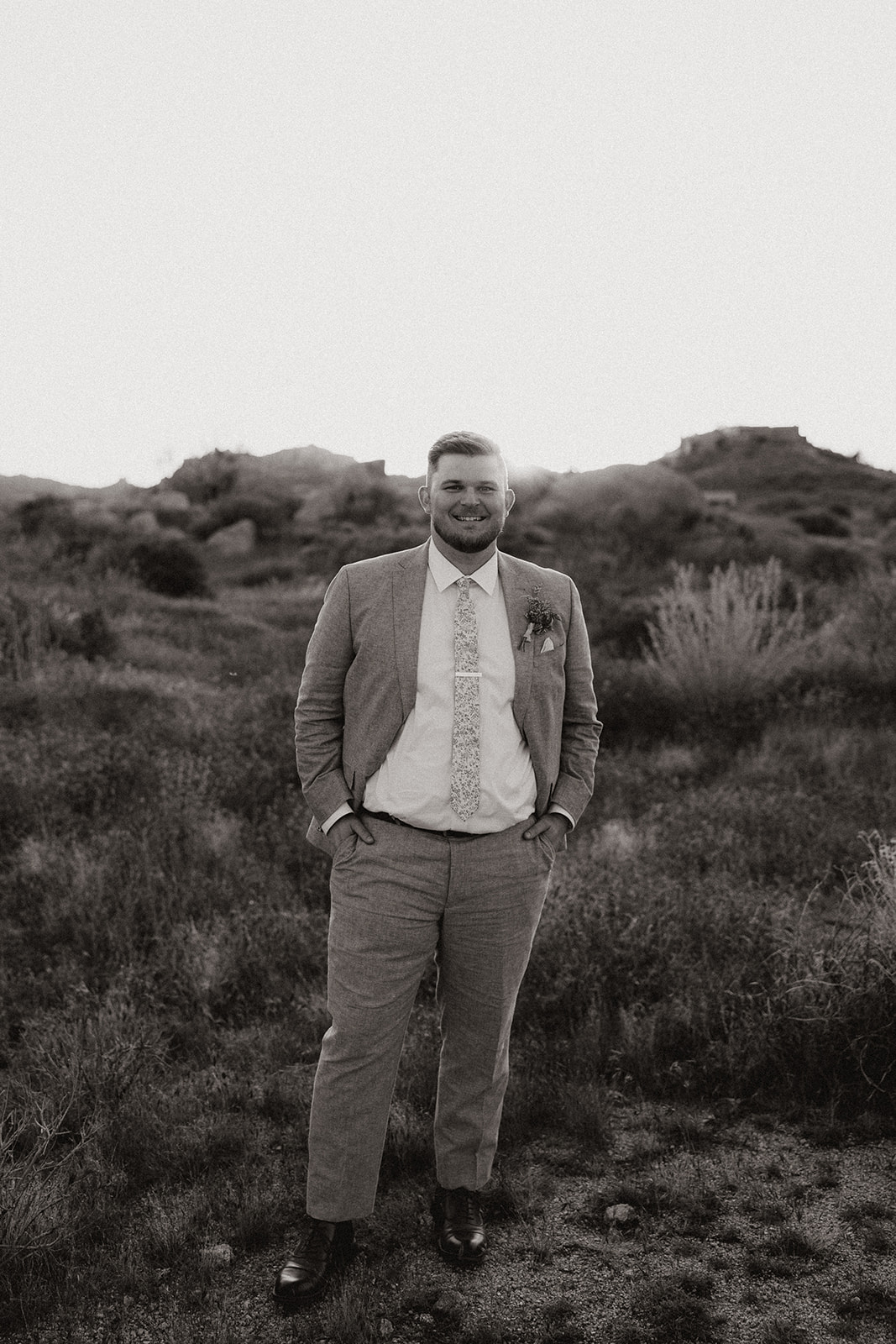 groom poses in the Arizona nature after his dreamy Arizona wedding day