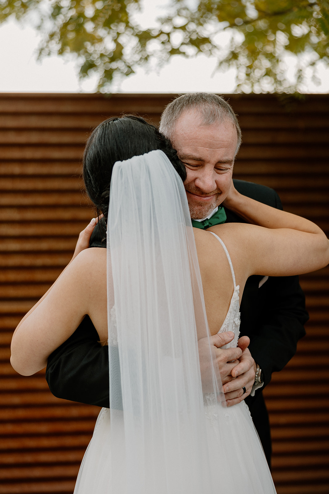 bride and father share a hug, make sure to include ample time for first look photos in your wedding day timeline!