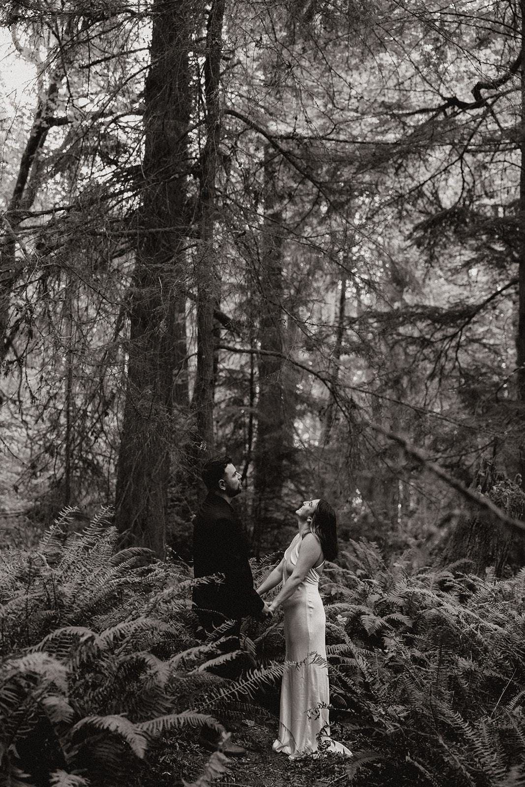 beautiful couple walk through the forest together during their PNW forest wedding anniversary photoshoot