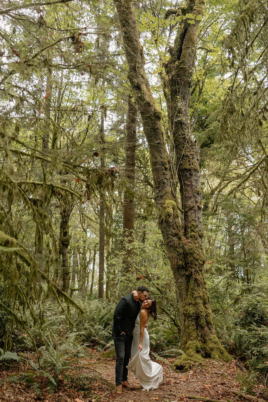 beautiful couple walk through the forest together during their PNW forest wedding anniversary photoshoot