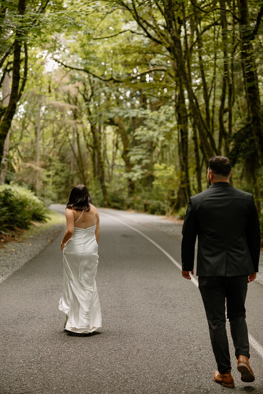 beautiful couple walk through on the forest road together during their PNW forest wedding anniversary photoshoot