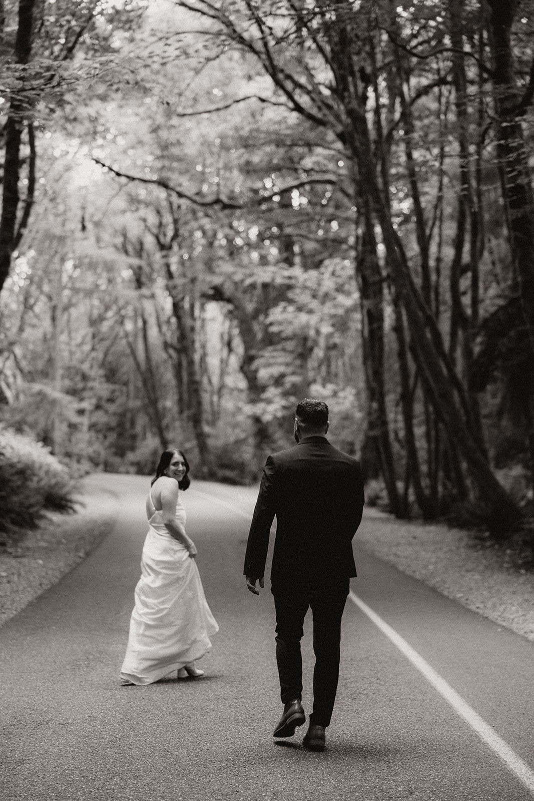 beautiful couple walk through on the forest road together during their PNW forest wedding anniversary photoshoot