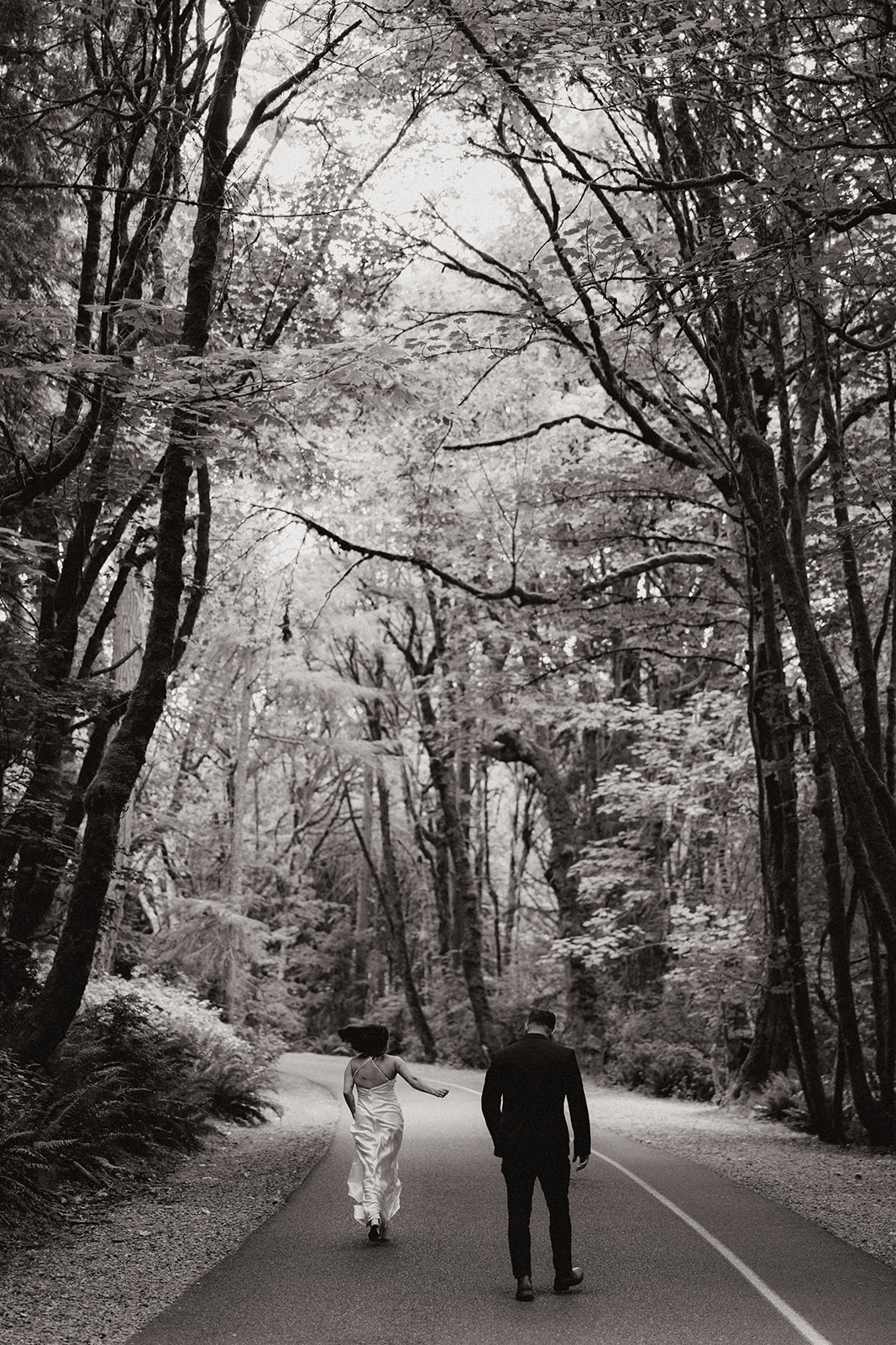 beautiful couple walk through on the forest road together during their PNW forest wedding anniversary photoshoot