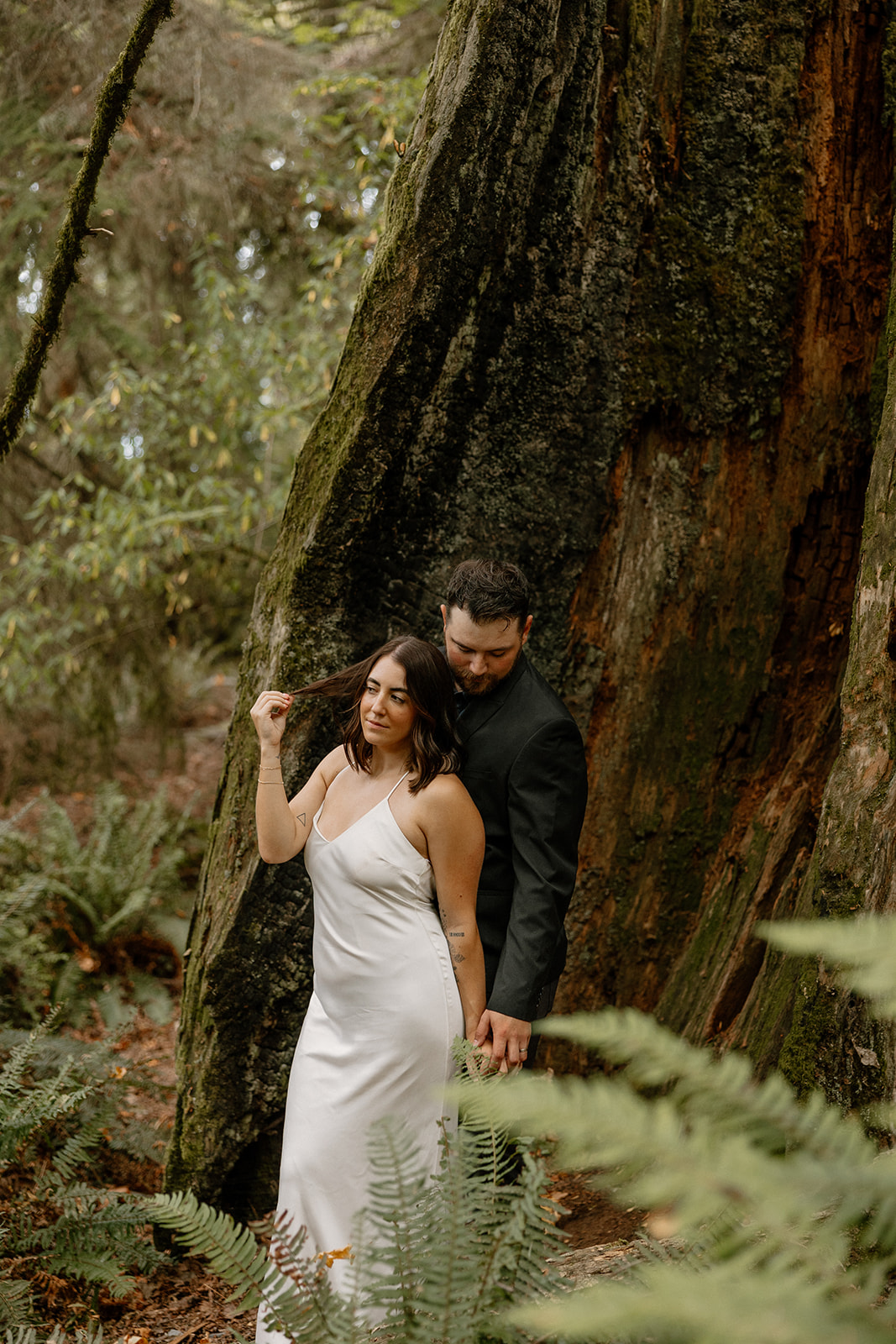 beautiful couple walk through the forest together during their PNW forest wedding anniversary photoshoot