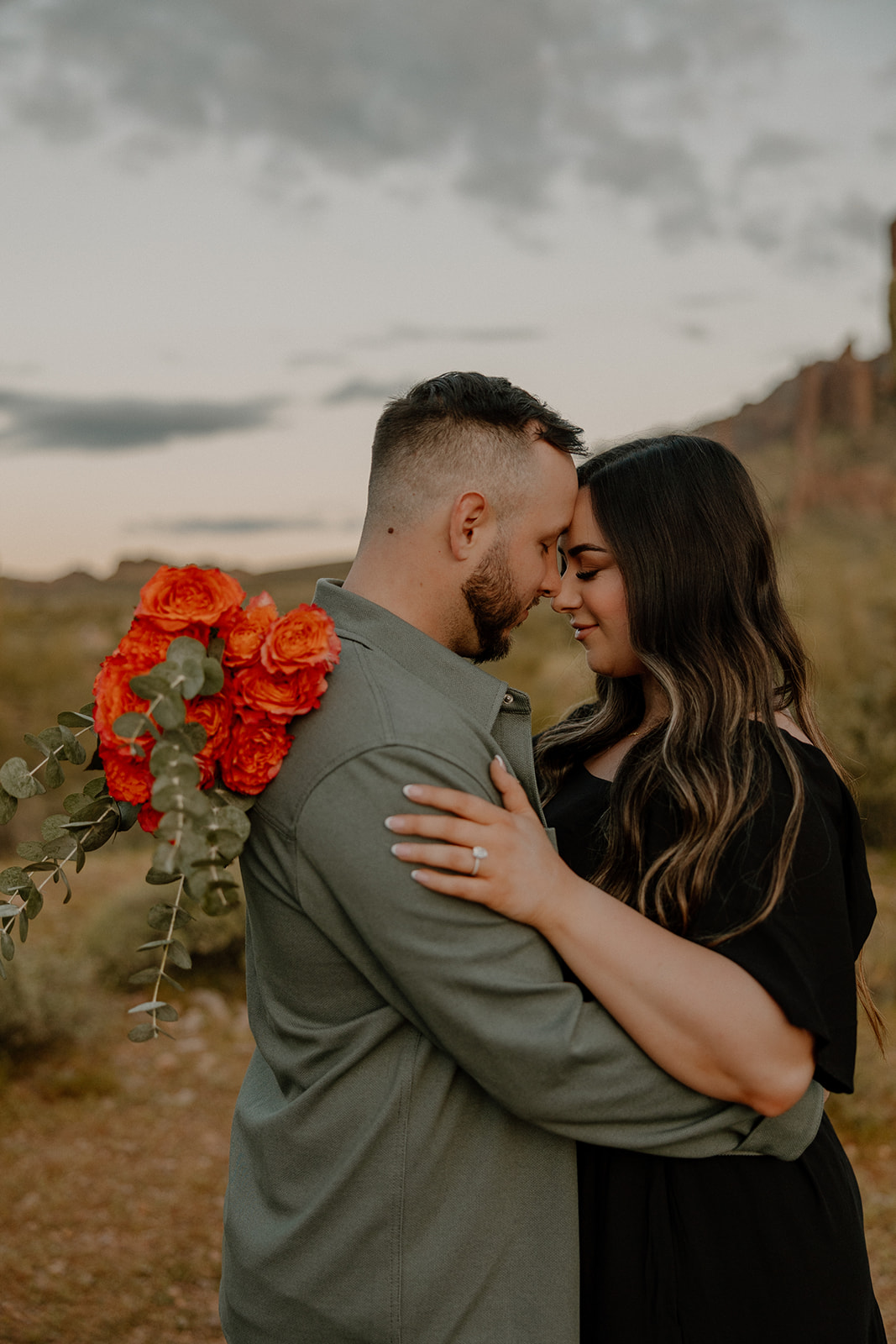 couple pose with red florals in the Arizona wilderness