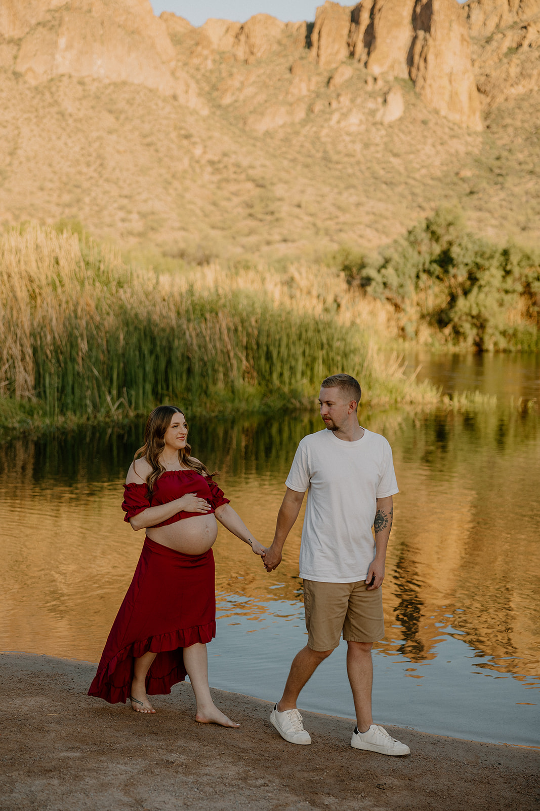 beautiful couple pose together beside the water during their water engagement photos