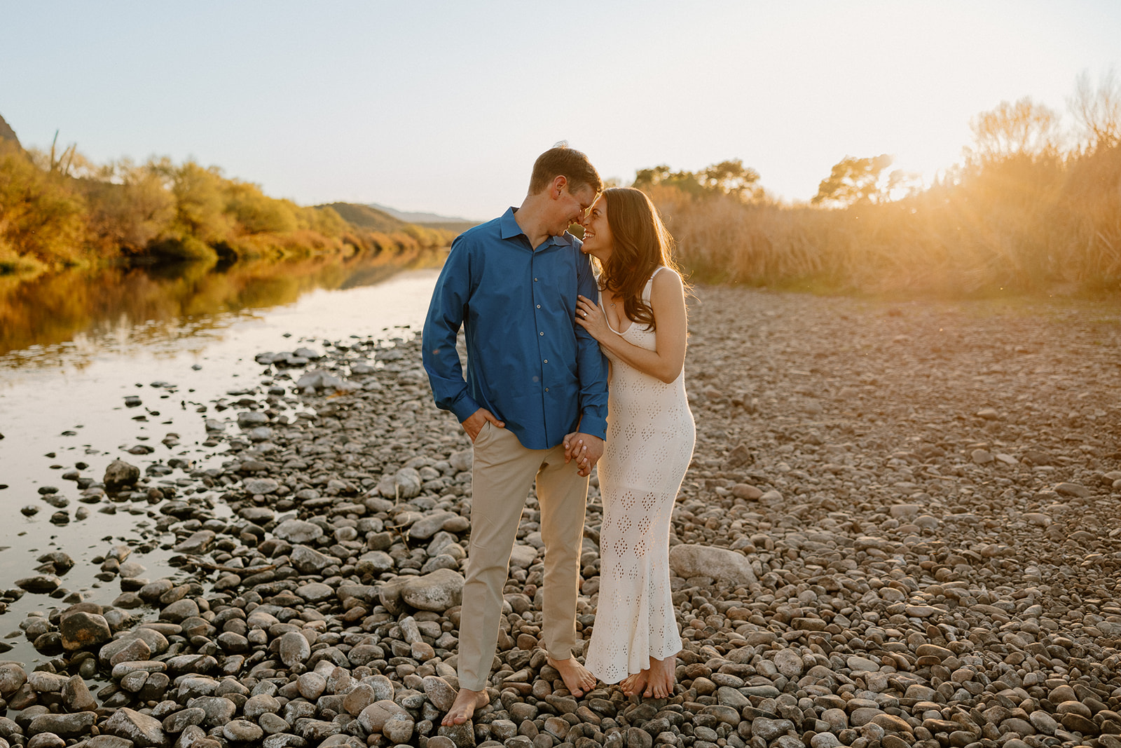 beautiful couple pose together beside the water during their water engagement photos