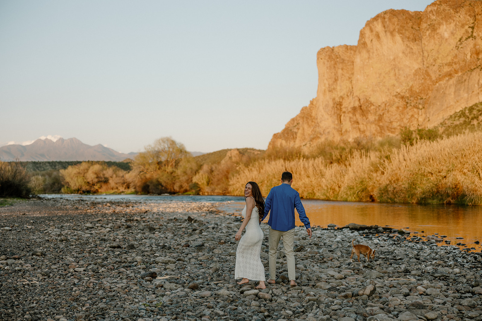 beautiful couple pose together beside the water during their water engagement photos