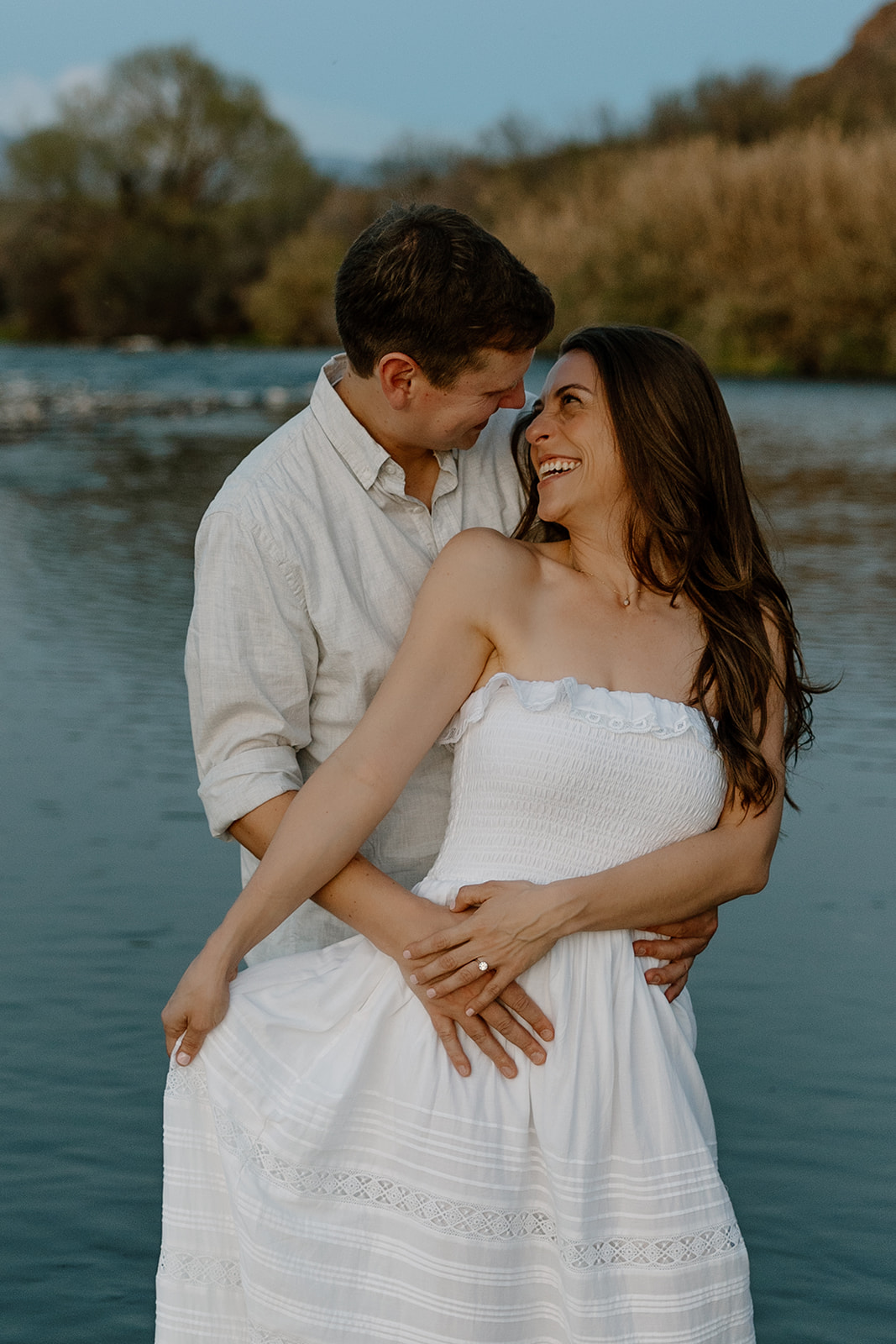 beautiful couple pose together beside the water during their water engagement photos