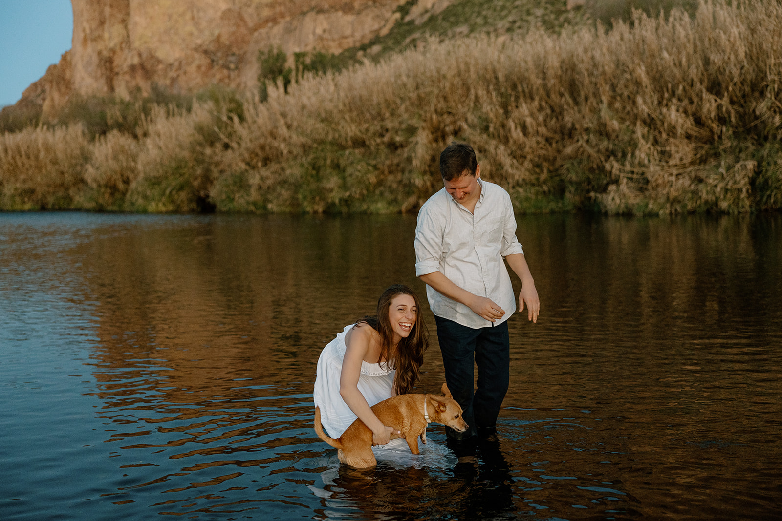 couple poses in the water with their dog