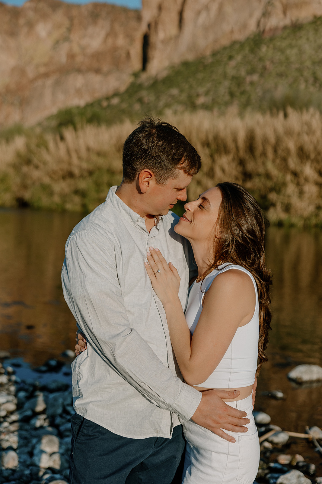 beautiful couple pose with their dog beside a river