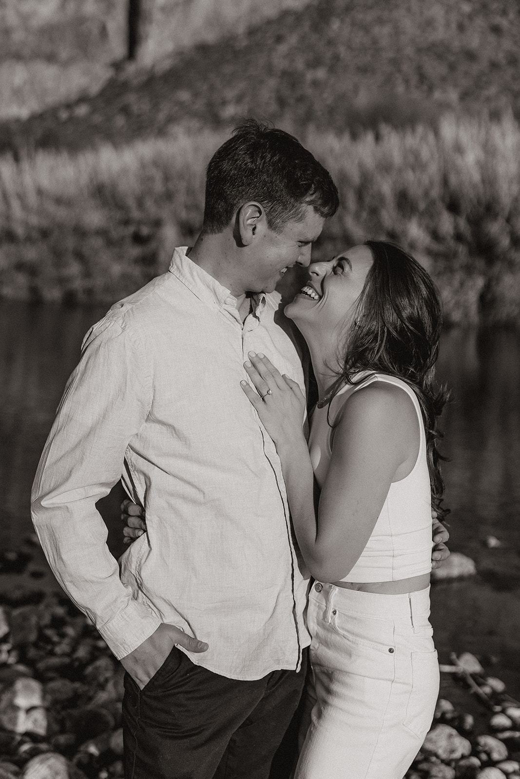 beautiful couple pose together beside the water during their water engagement photos