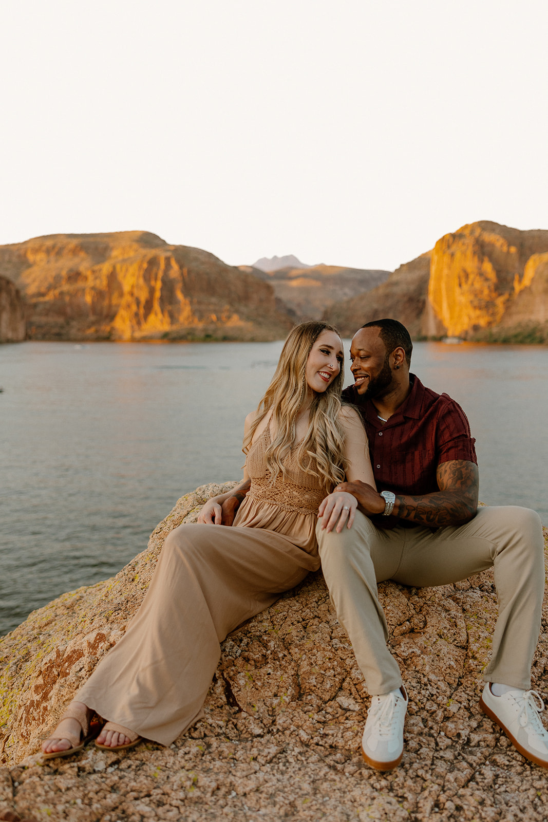 beautiful couple pose together beside the water during their water engagement photos