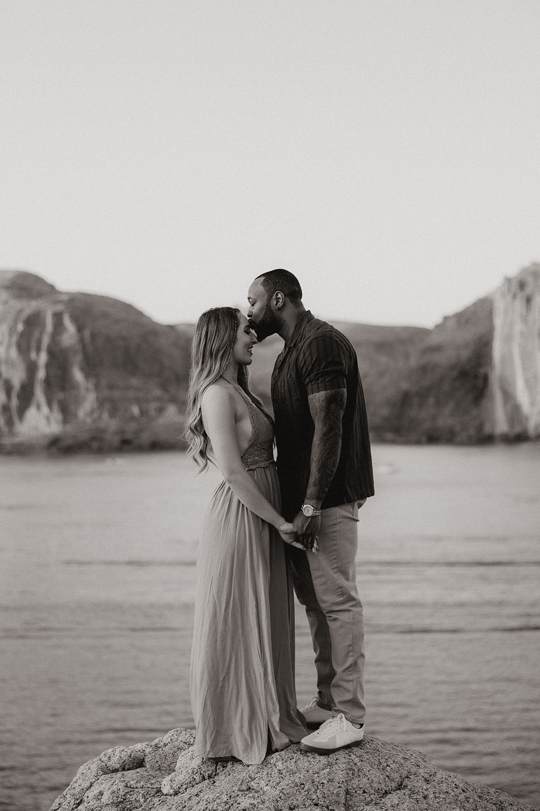 beautiful couple pose together beside the water during their water engagement photos