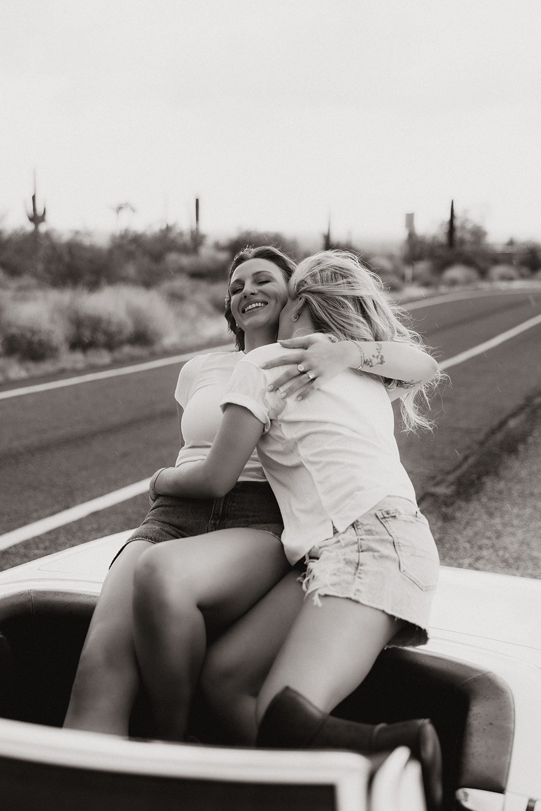 stunning couple pose with a vintage car during their engagement photos in the Arizona dessert