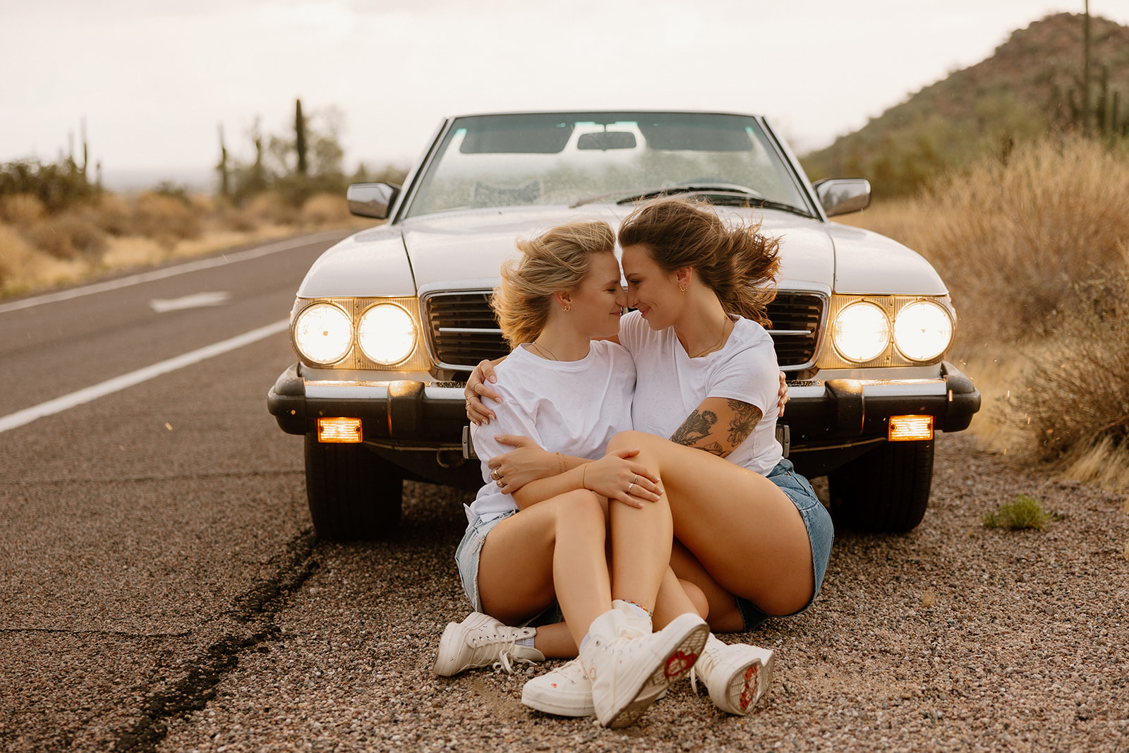 stunning couple pose with a vintage car during their engagement photos in the Arizona dessert