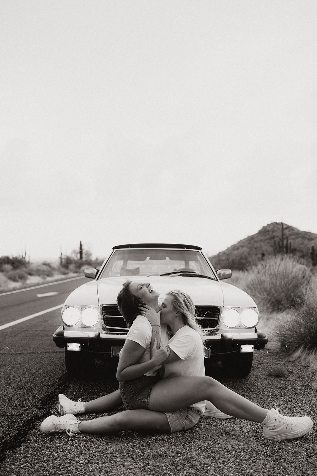 stunning couple pose with a vintage car during their engagement photos in the Arizona dessert