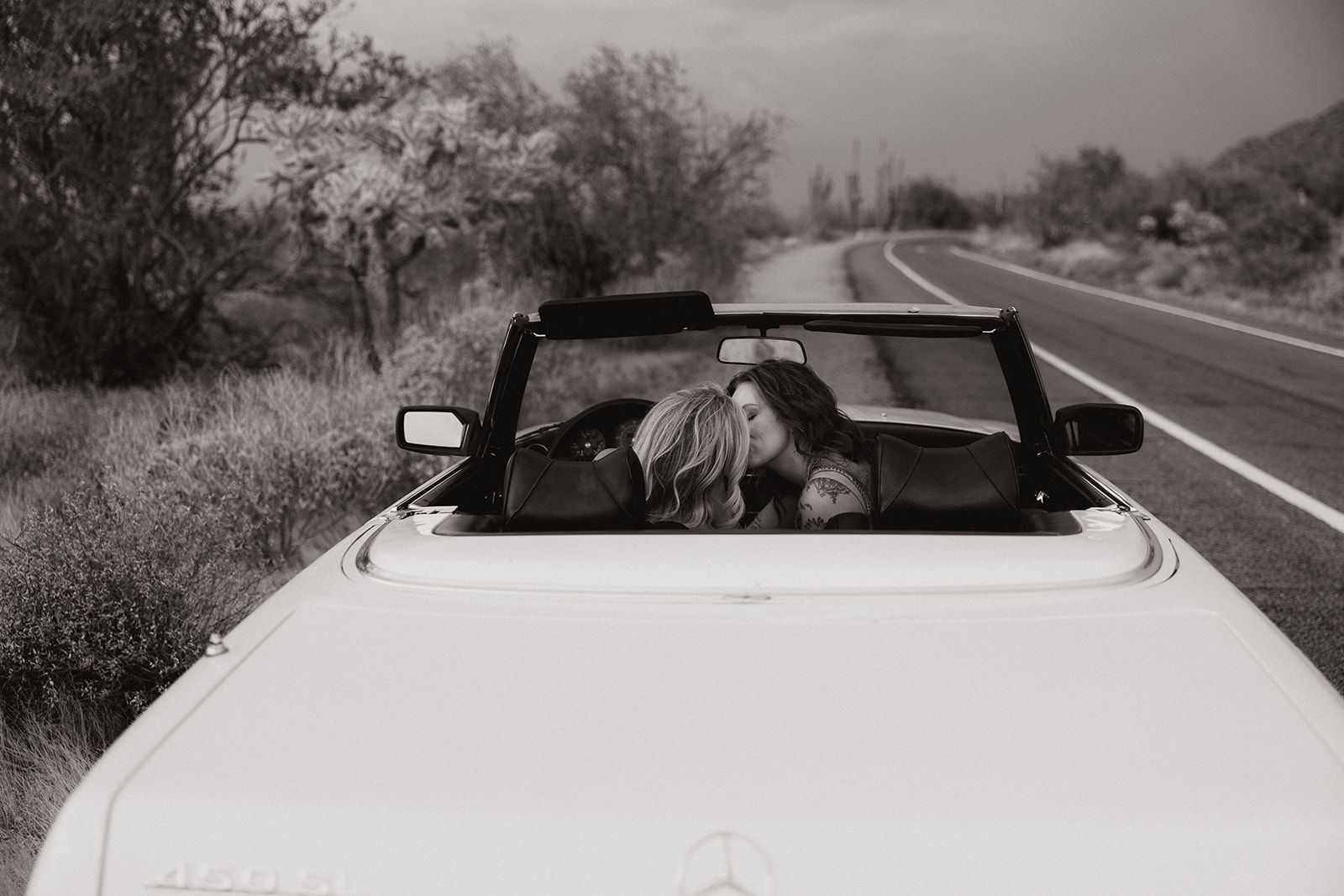 stunning couple pose with a vintage car during their engagement photos in the Arizona dessert