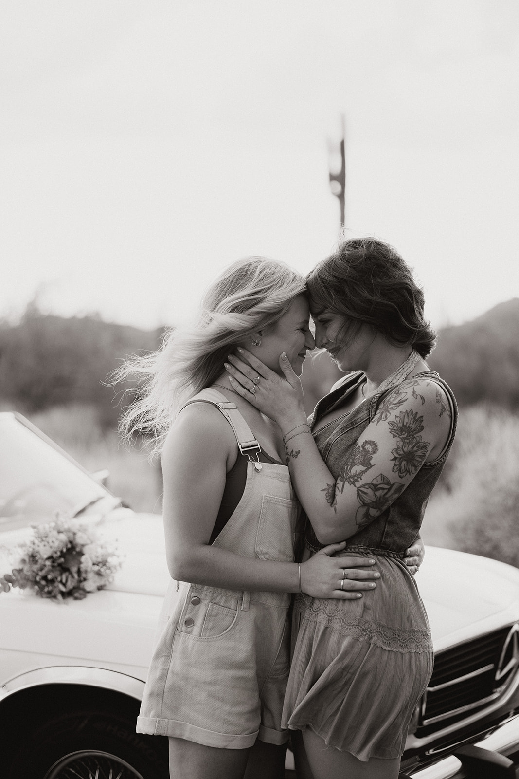 stunning couple pose with a vintage car during their engagement photos in the Arizona dessert