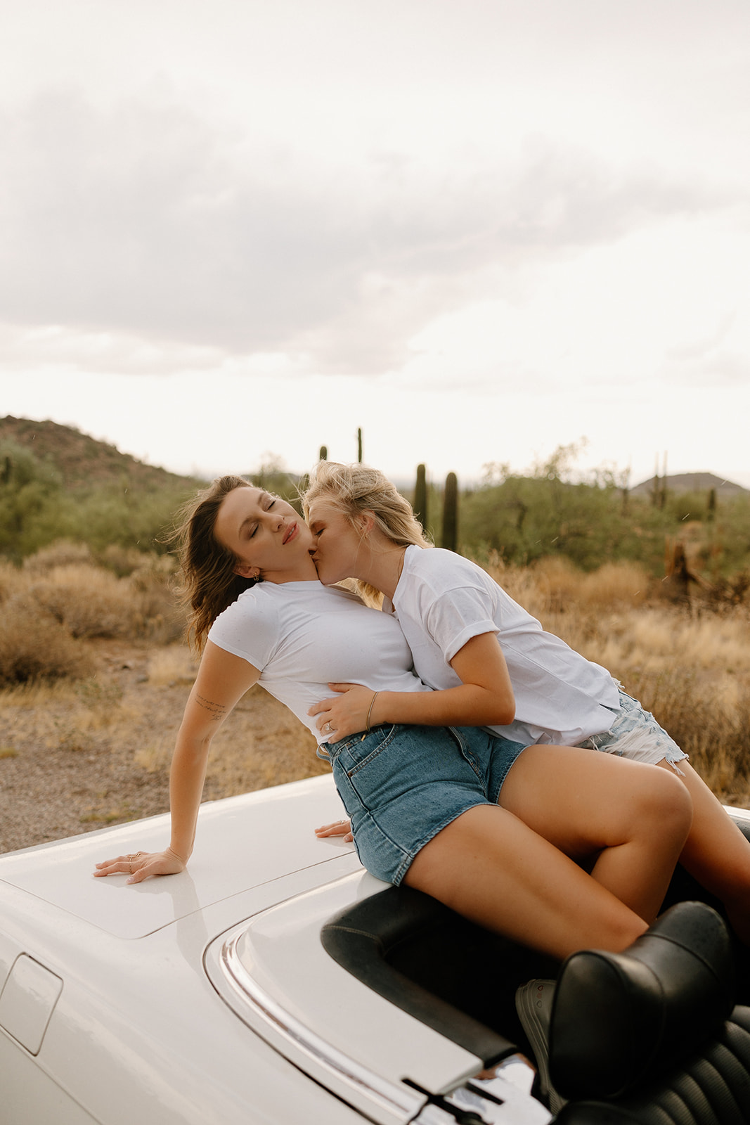 stunning couple pose with a vintage car during their engagement photos in the Arizona dessert