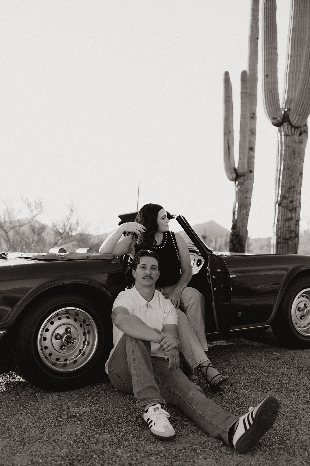 stunning couple pose with a vintage car during their engagement photos in the Arizona dessert