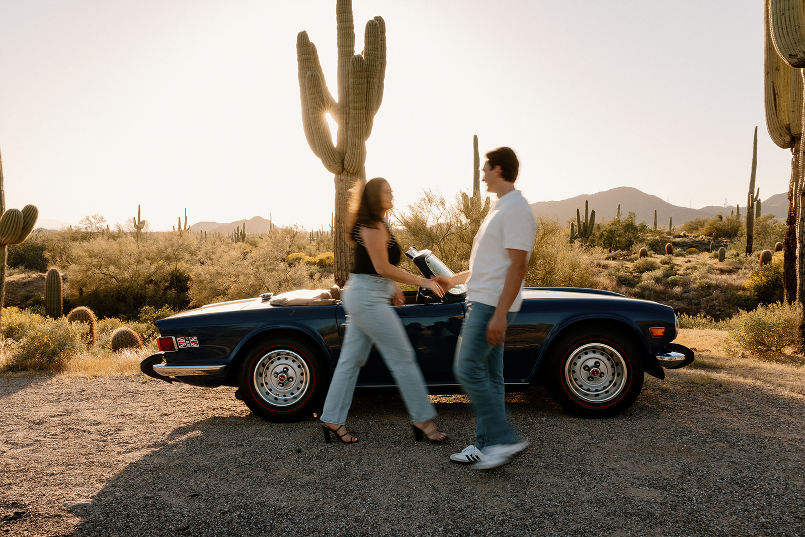 stunning couple pose with a vintage car during their engagement photos in the Arizona dessert