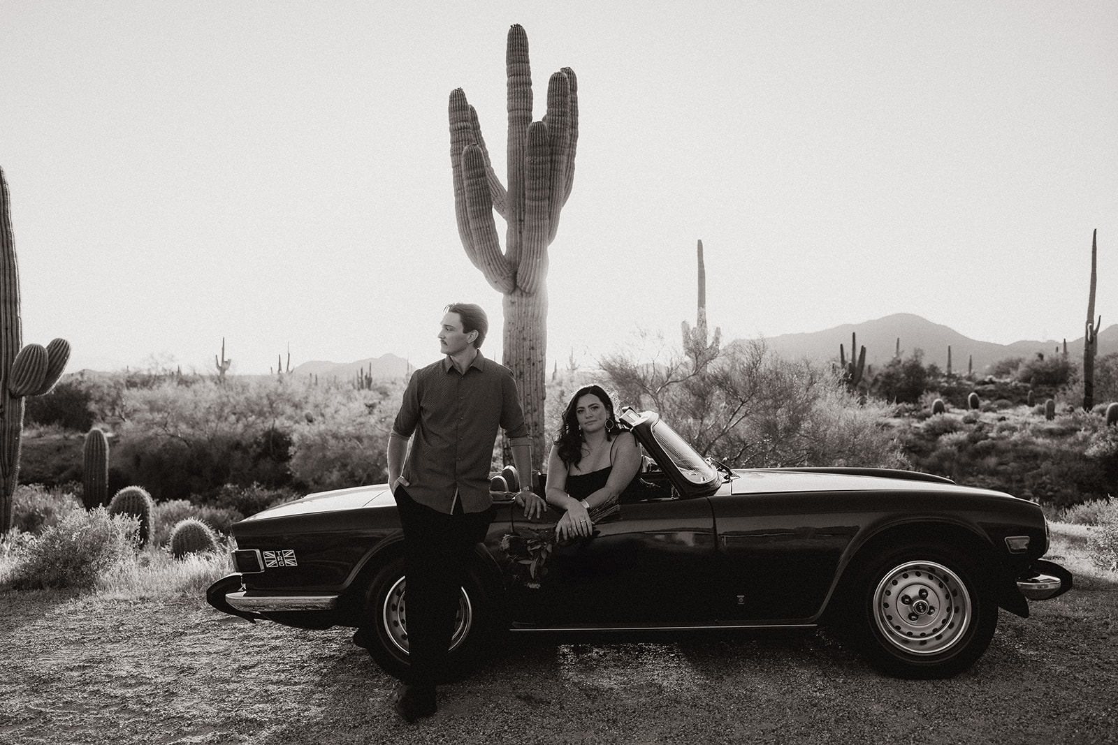 stunning couple pose with a vintage car during their engagement photos in the Arizona dessert