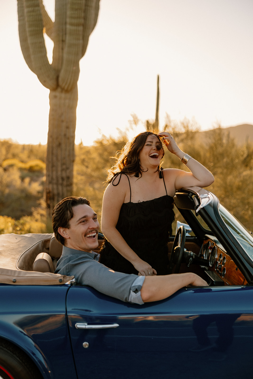 stunning couple pose with a vintage car during their engagement photos in the Arizona dessert